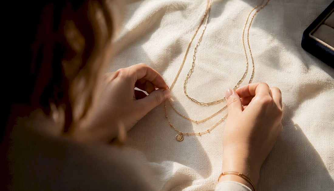 Hands layering gold necklaces