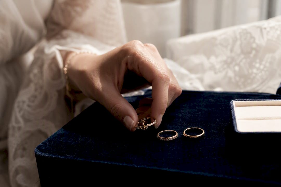 Hand stacking elegant rings on cream surface