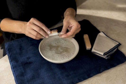 Hands gently cleaning jewelry with soft brush