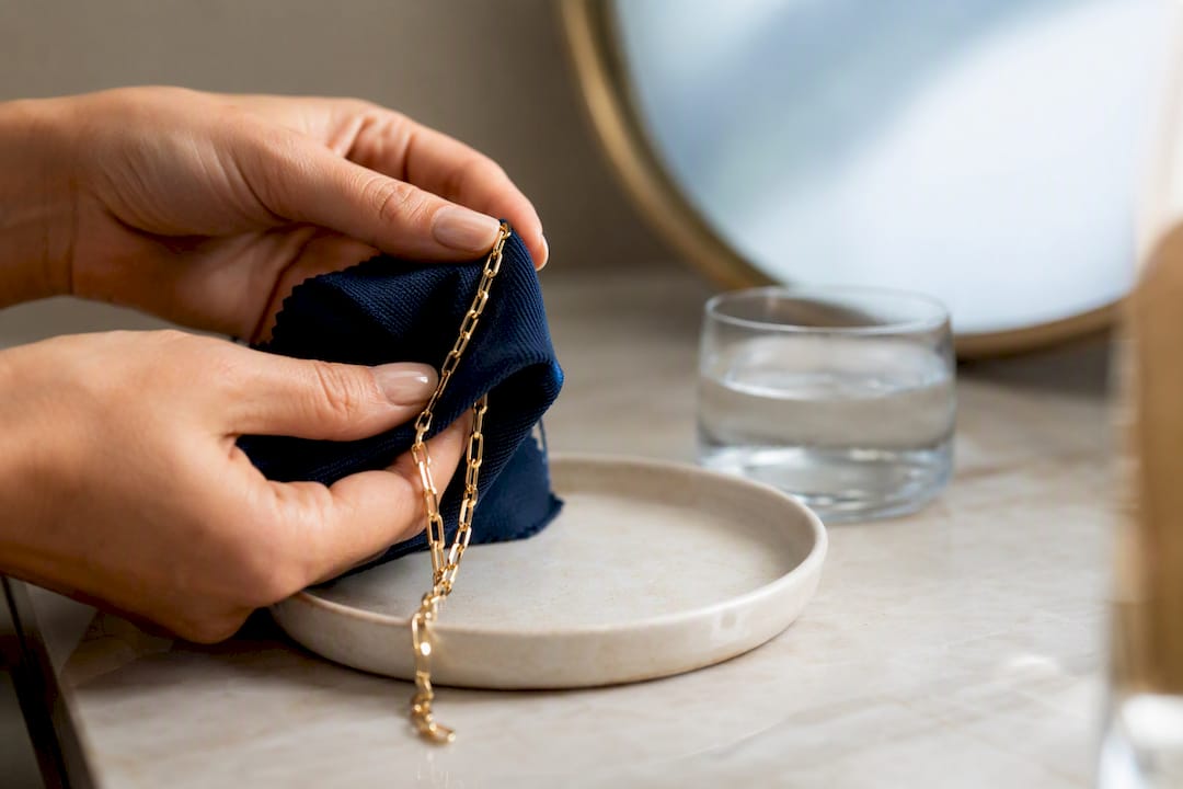 Hands gently cleaning gold plated jewelry